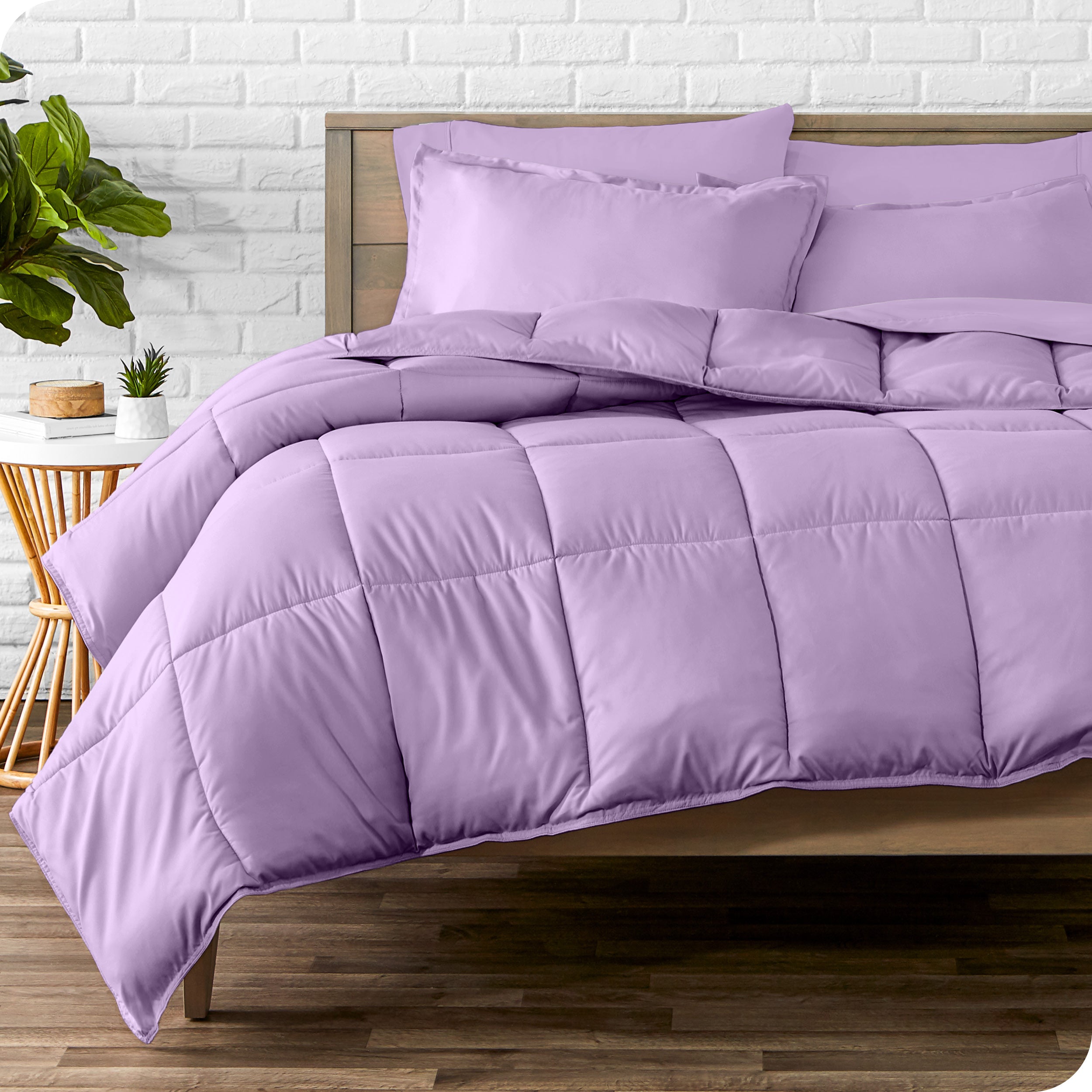 A wooden bed frame with sheets, pillow shams and a comforter on the bed