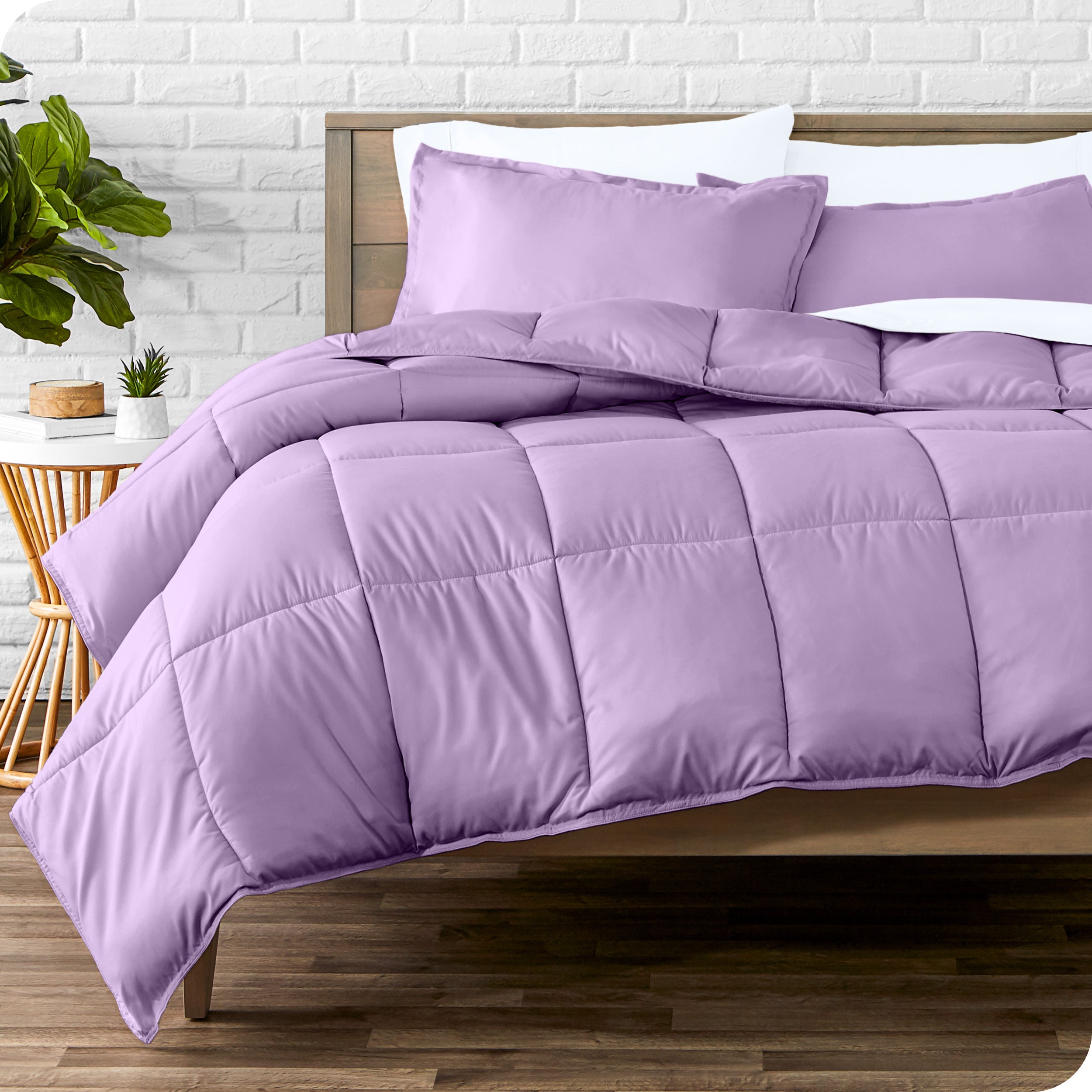 A wooden bed frame with sheets, pillow shams and a comforter on the bed