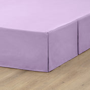 A box spring with a bed skirt on it