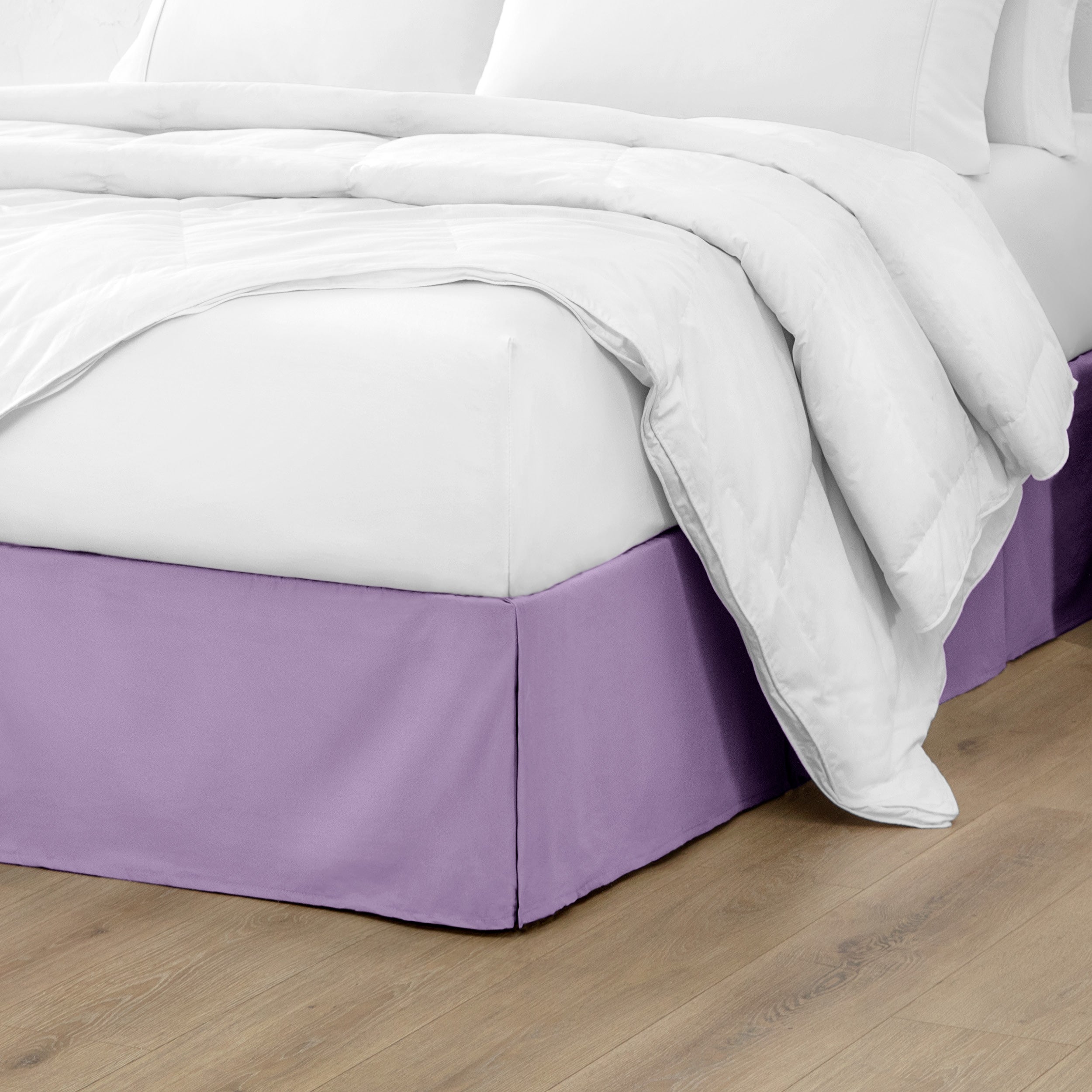 The corner of a bed with a bed skirt and comforter on it