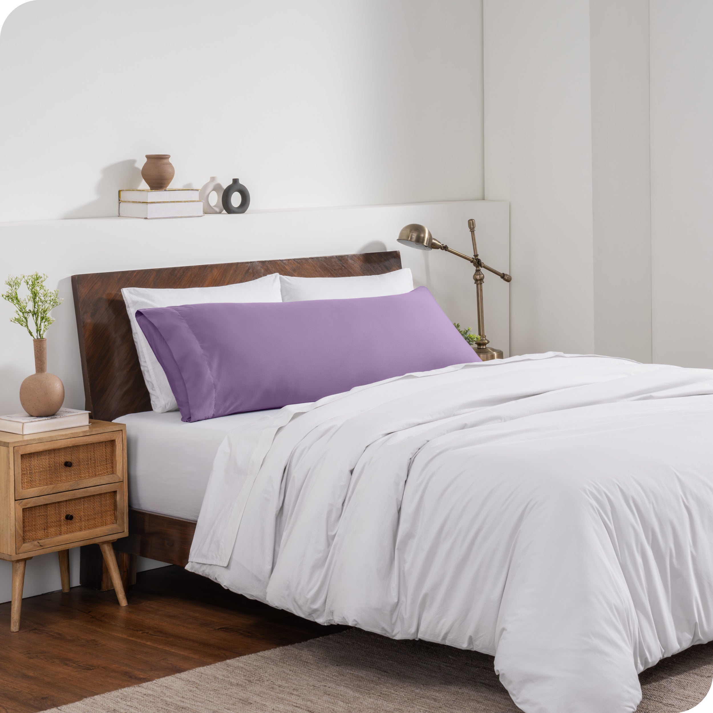 A body pillow cover on a pillow on a bed made with all white bedding
