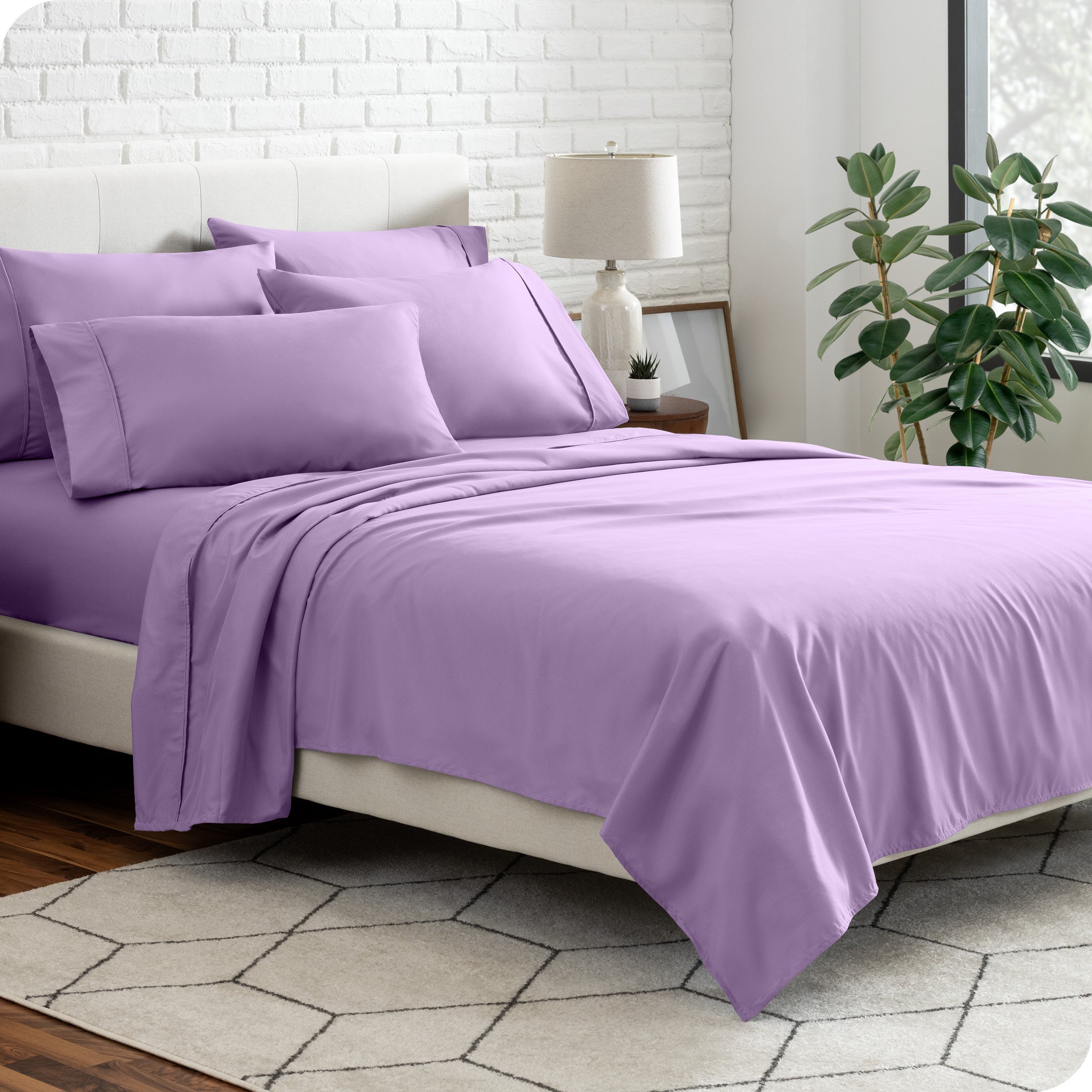 A bedroom setting with a bed made with the microfiber bed sheets and four pillows.