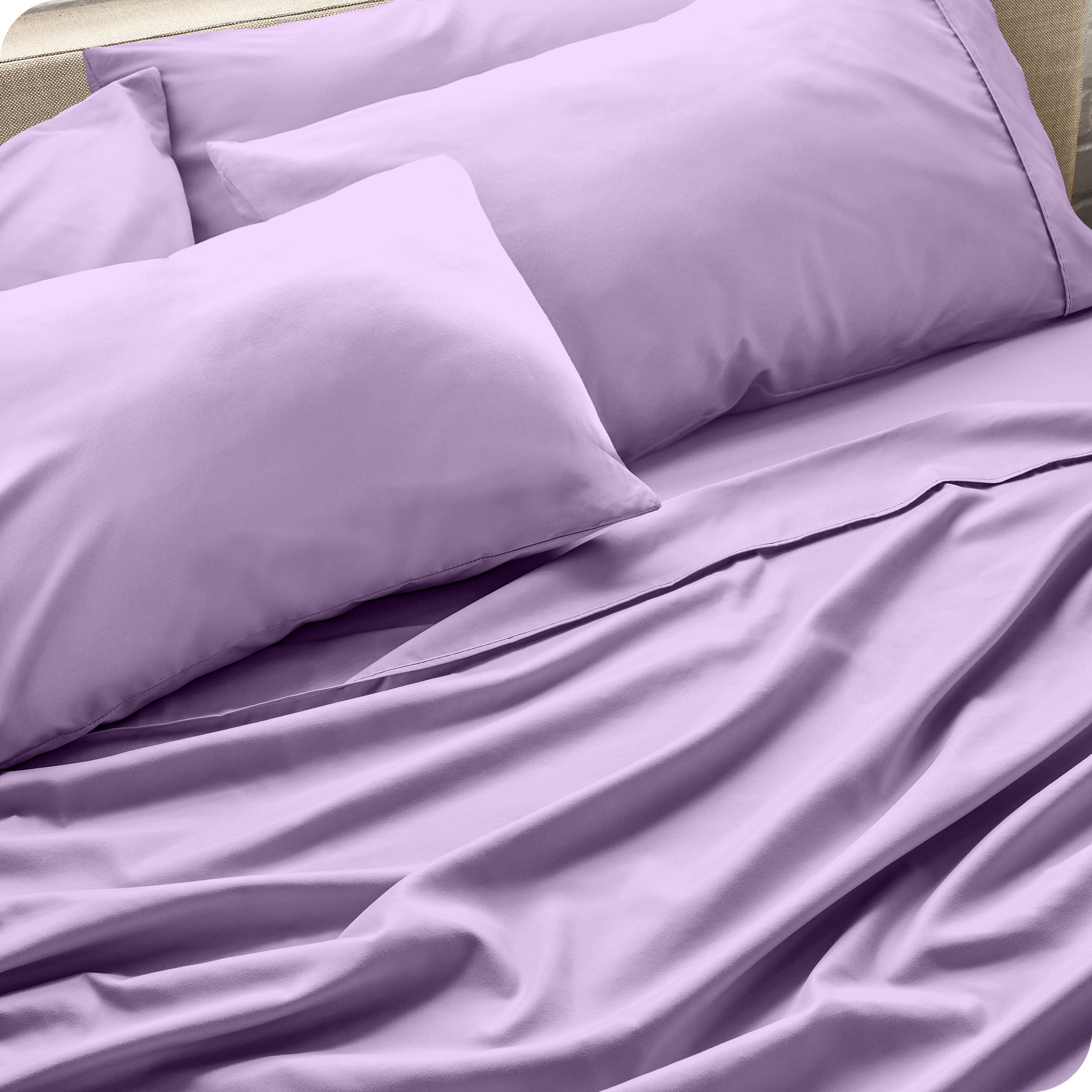 Close up of the microfiber bed sheets on a bed with four pillows.