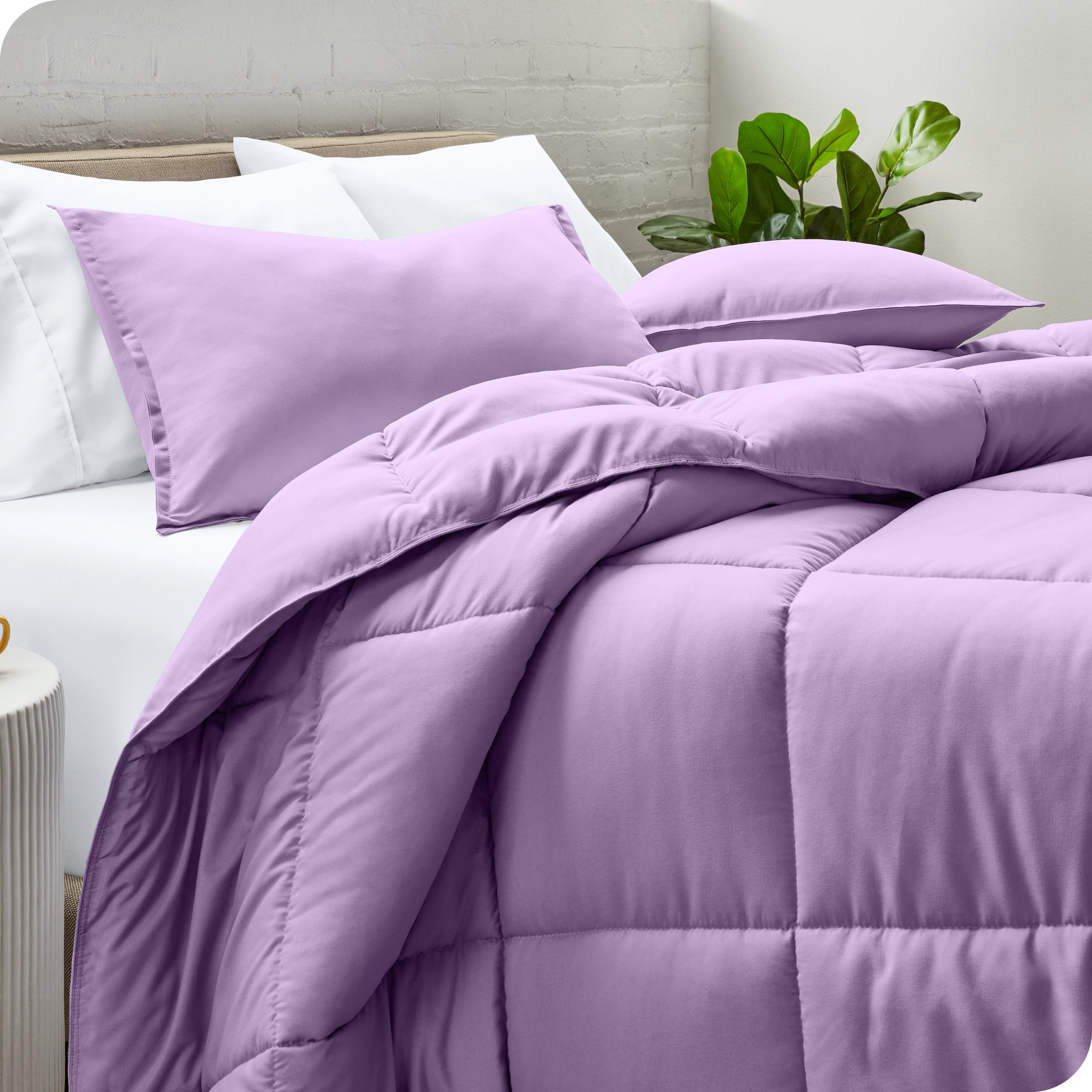 A side view of a modern bed with a comforter set and pillows on the bed