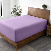 A wide corner view of a modern bed made with a microfiber fitted sheet on the mattress. 