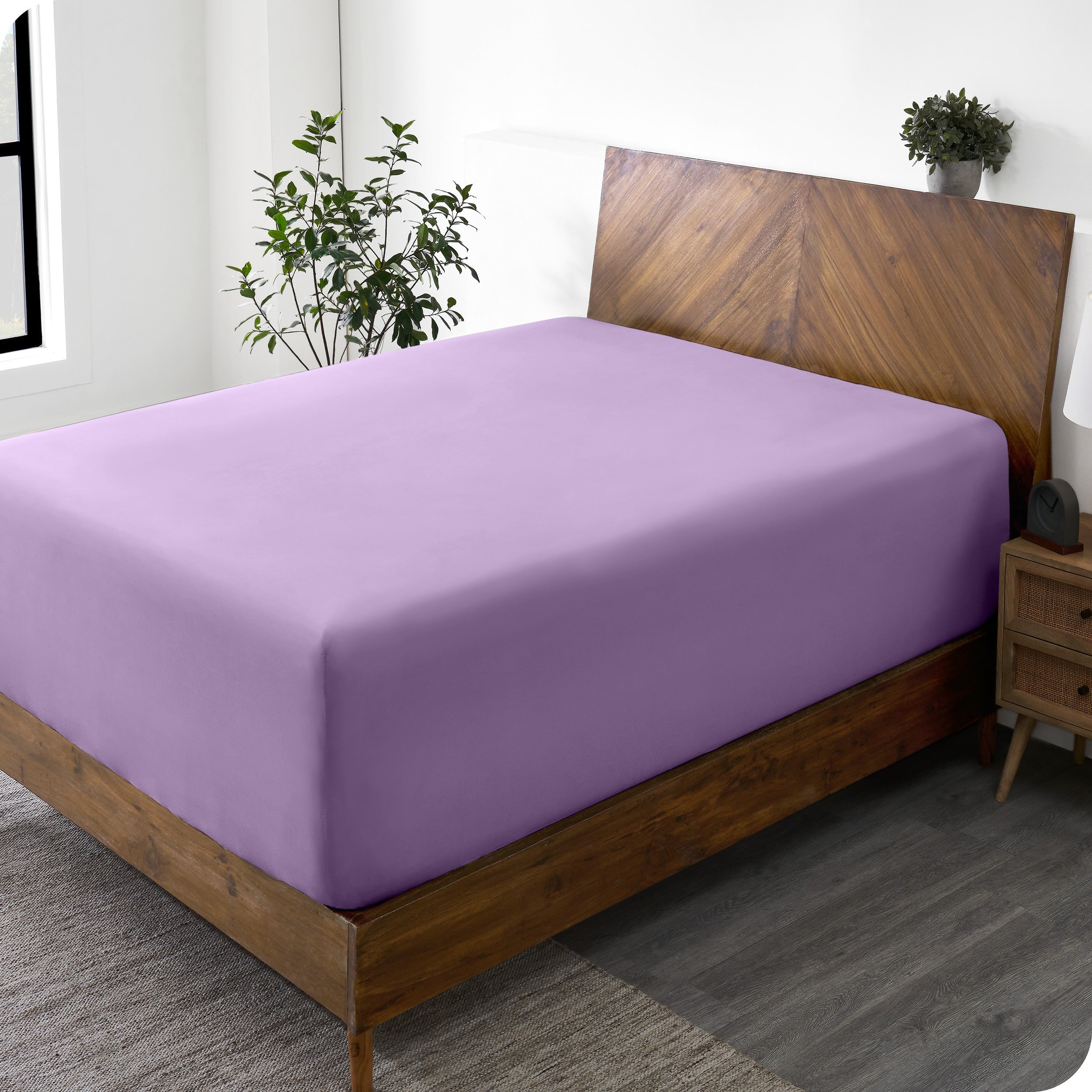 A wide corner view of a modern bed made with a microfiber fitted sheet on the mattress. 