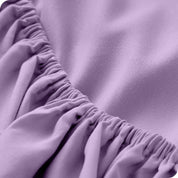 A modern bed with a fitted microfiber sheet on it