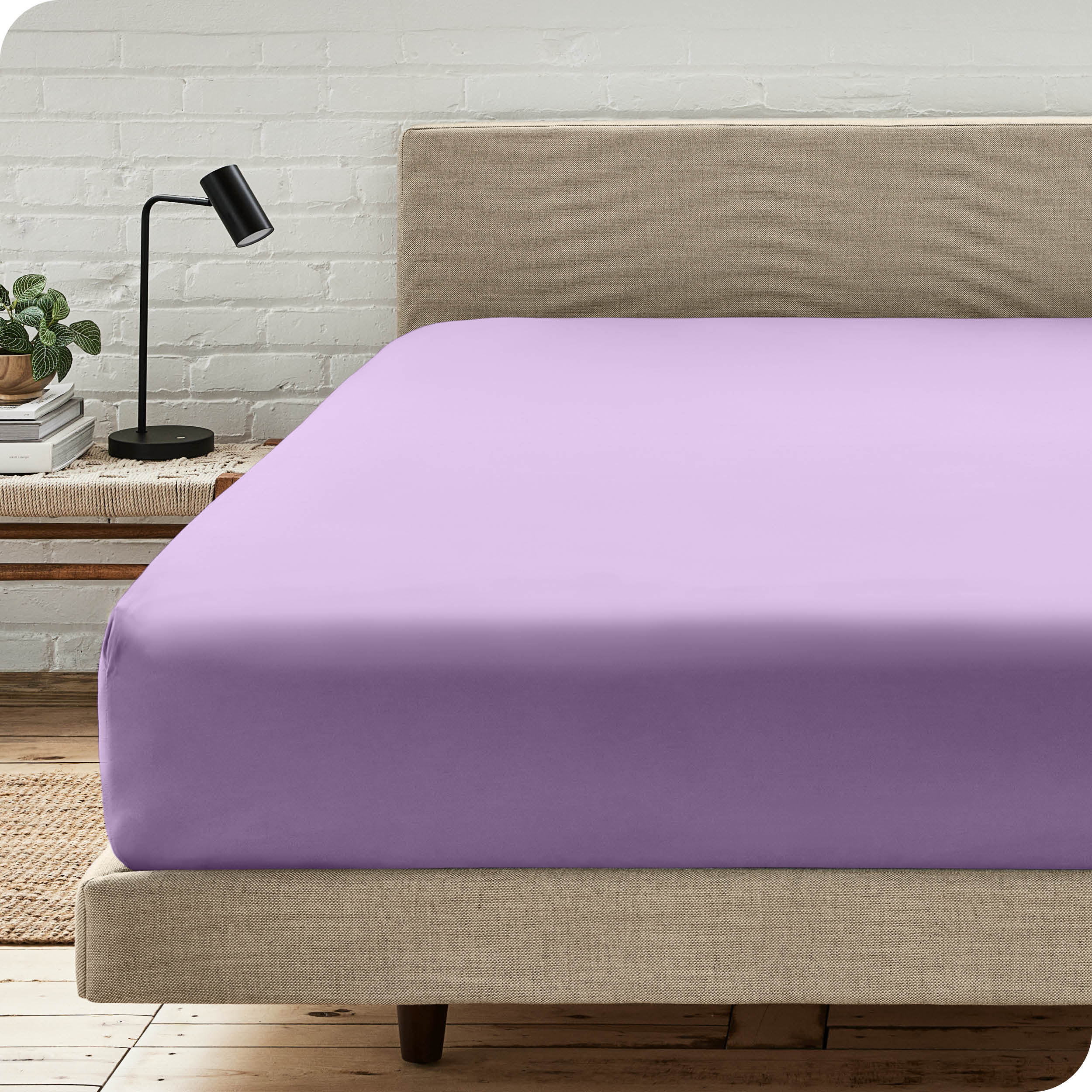 A bed with a microfiber fitted sheet on the mattress. 
