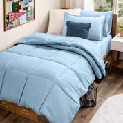 A college dorm room with a bed in a bag set on the mattress