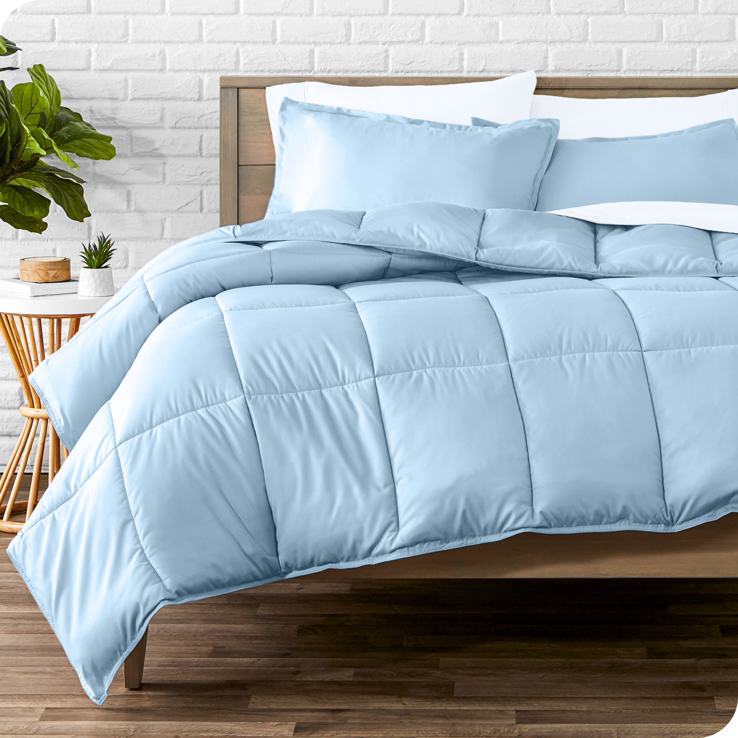 A wooden bed frame with sheets, pillow shams and a comforter on the bed