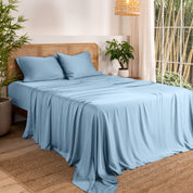 Bamboo sheets on a bed in a bedroom with plants and a window.