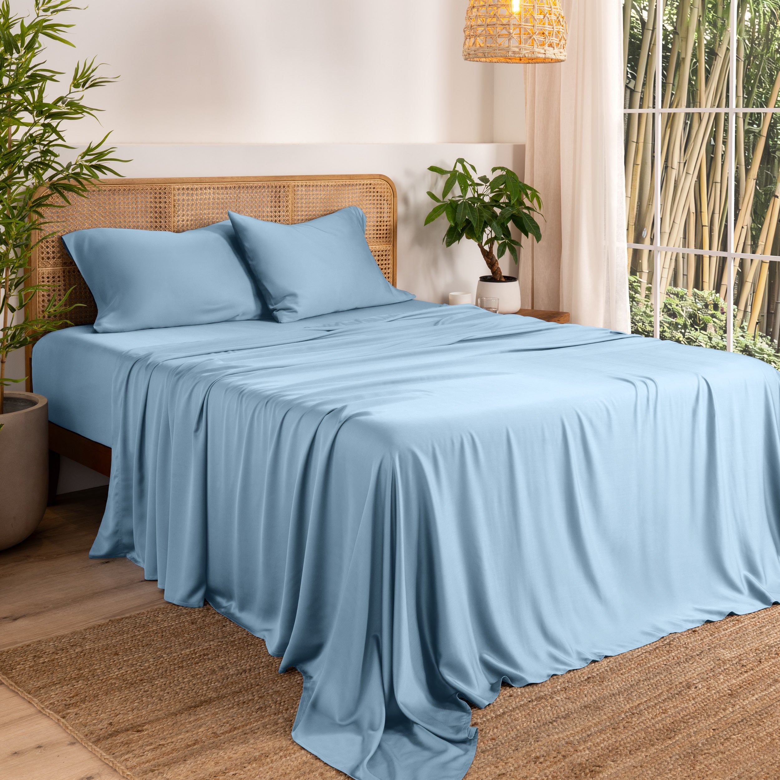 Bamboo sheets on a bed in a bedroom with plants and a window.