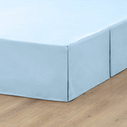 A box spring with a bed skirt on it