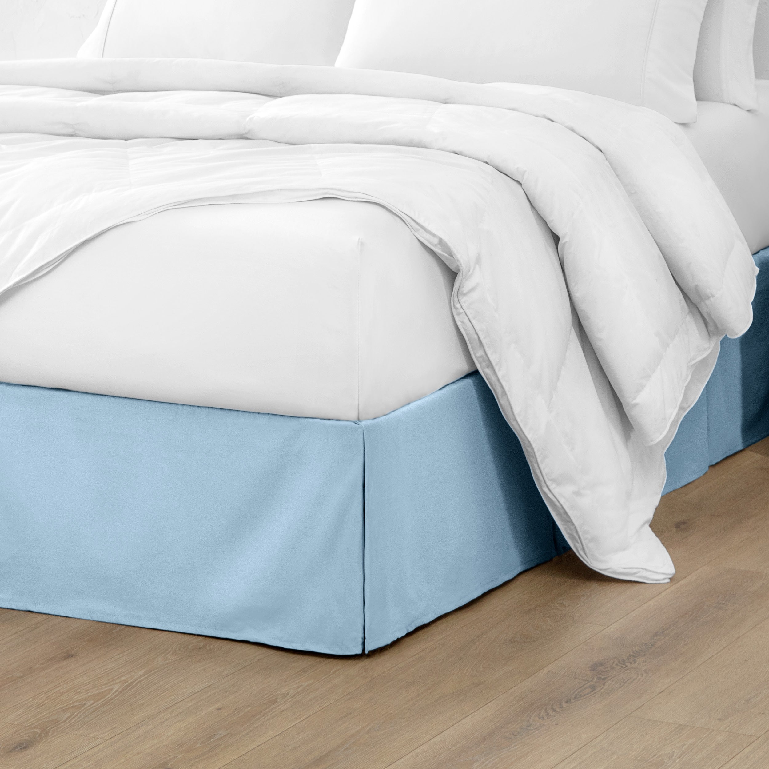 The corner of a bed with a bed skirt and comforter on it
