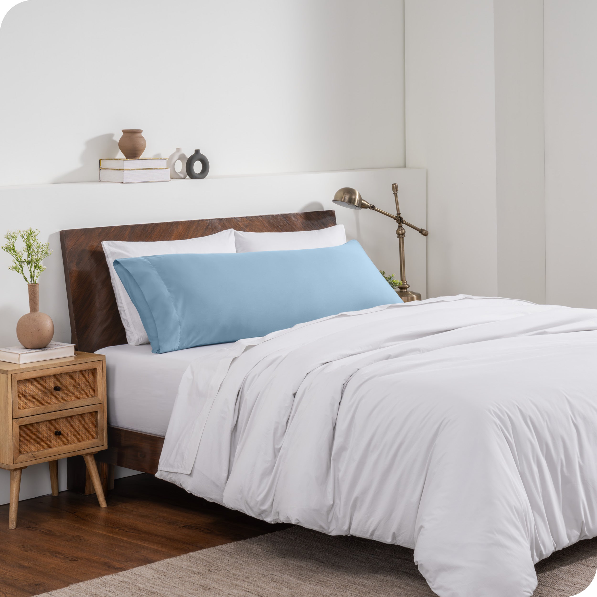 A body pillow cover on a pillow on a bed made with all white bedding