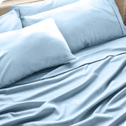 Close up of the microfiber bed sheets on a bed with four pillows.
