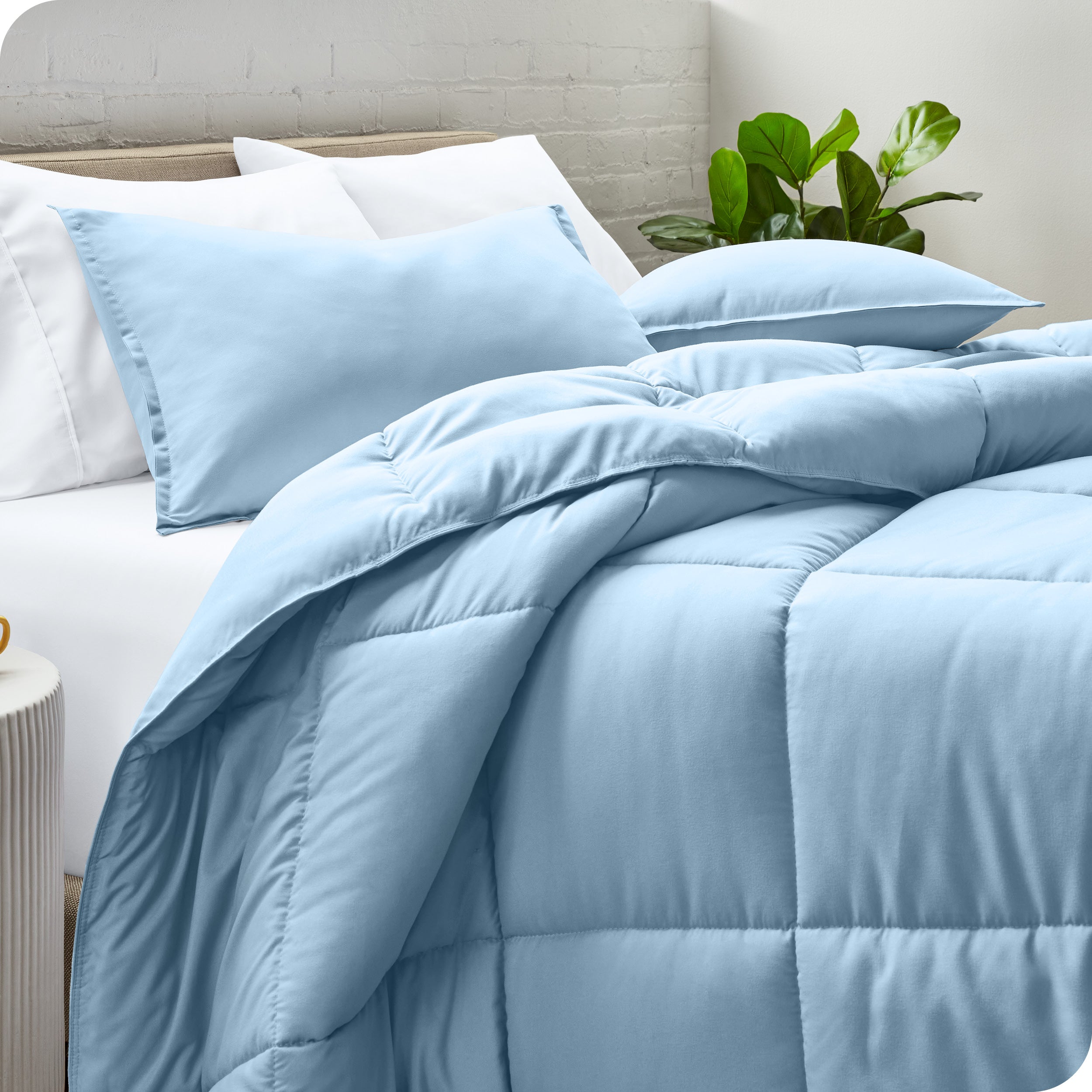A side view of a modern bed with a comforter set and pillows on the bed