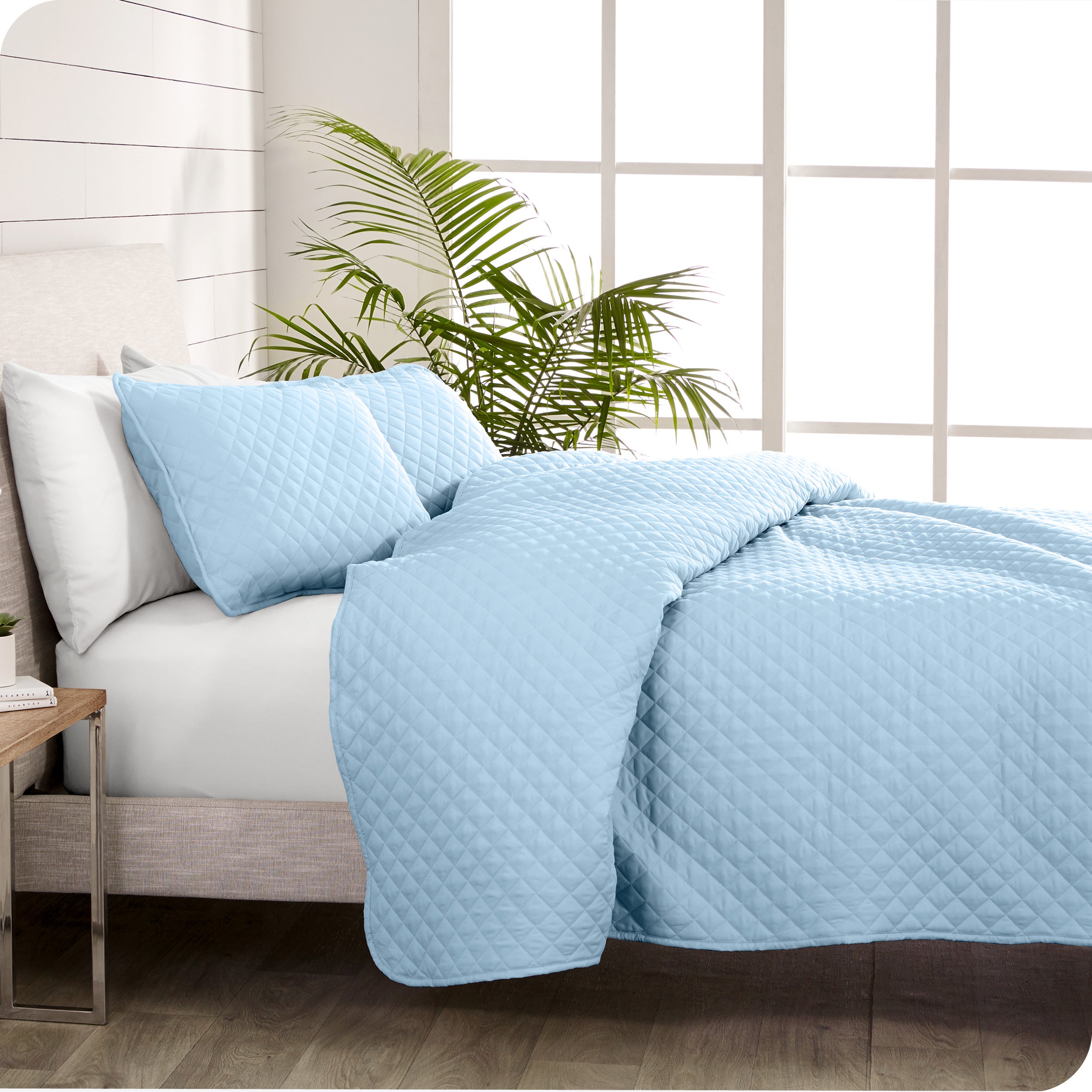 A coverlet set on a bed next to a window