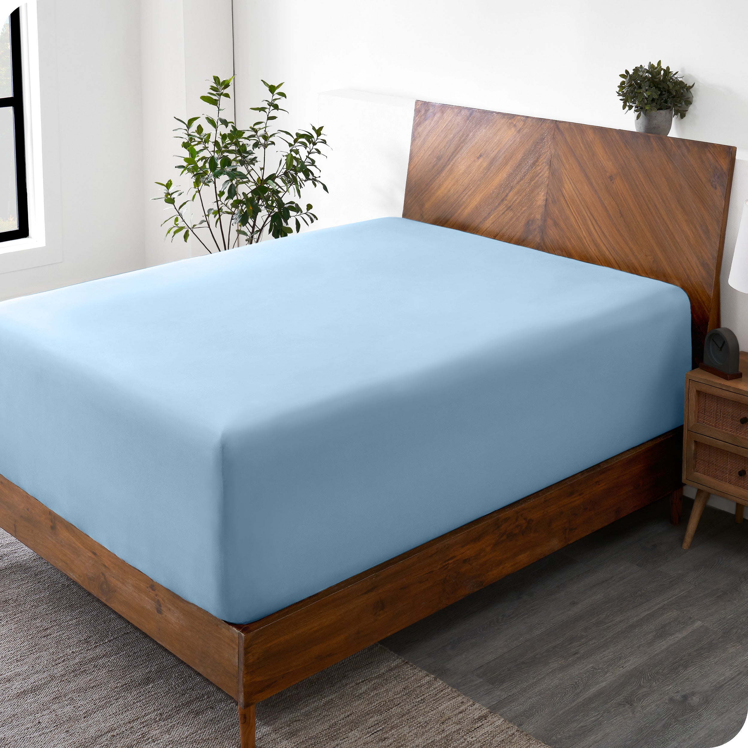 A wide corner view of a modern bed made with a microfiber fitted sheet on the mattress. 