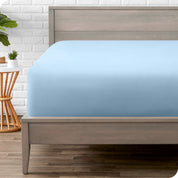 A modern bed with a fitted microfiber sheet on it