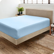 Corner view of a modern bed with a microfiber fitted sheet on the mattress. 