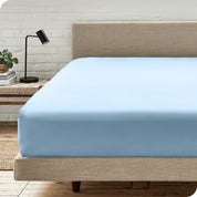 A bed with a microfiber fitted sheet on the mattress. 