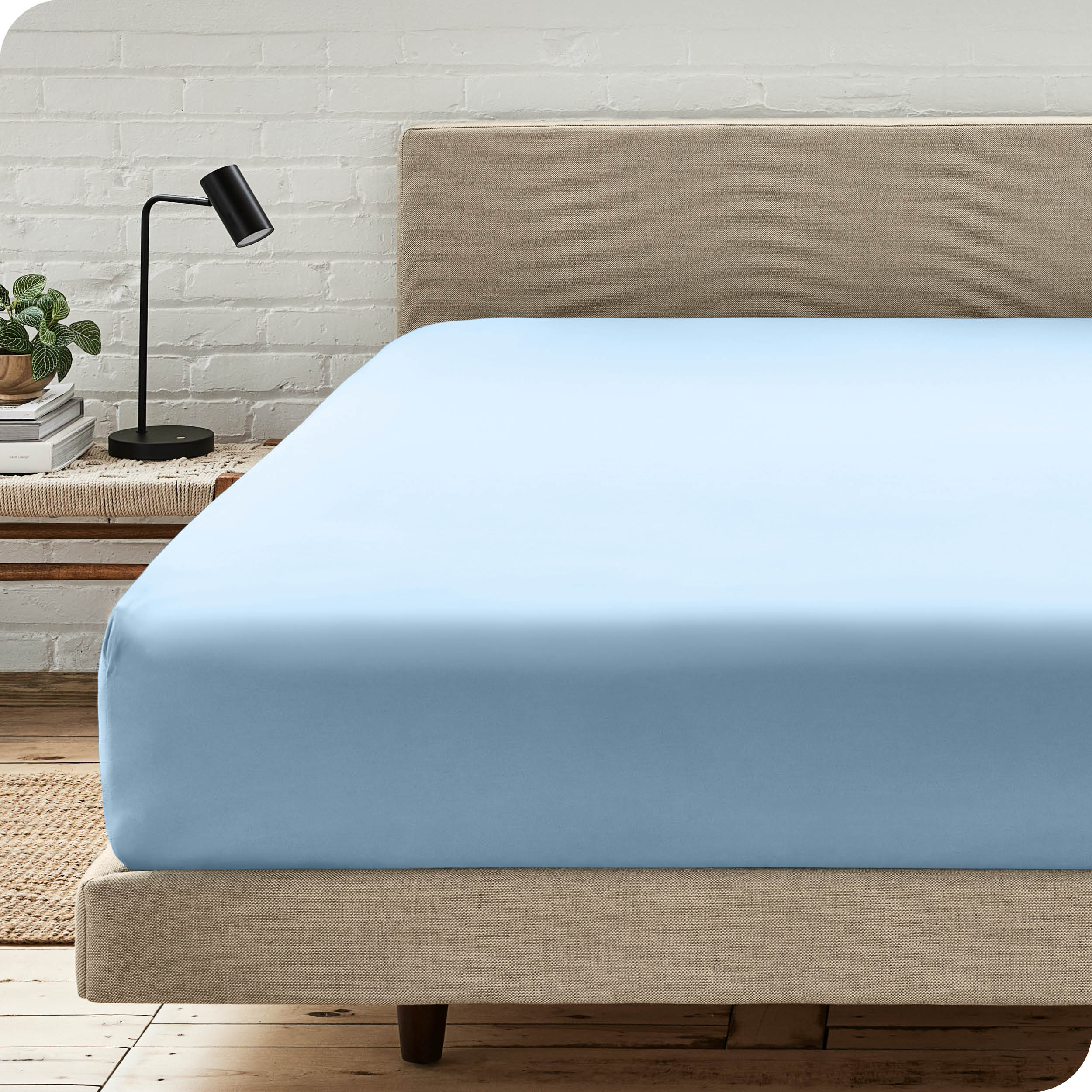 A bed with a microfiber fitted sheet on the mattress. 