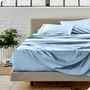 Microfiber sheets on a bed with a brick wall behind it