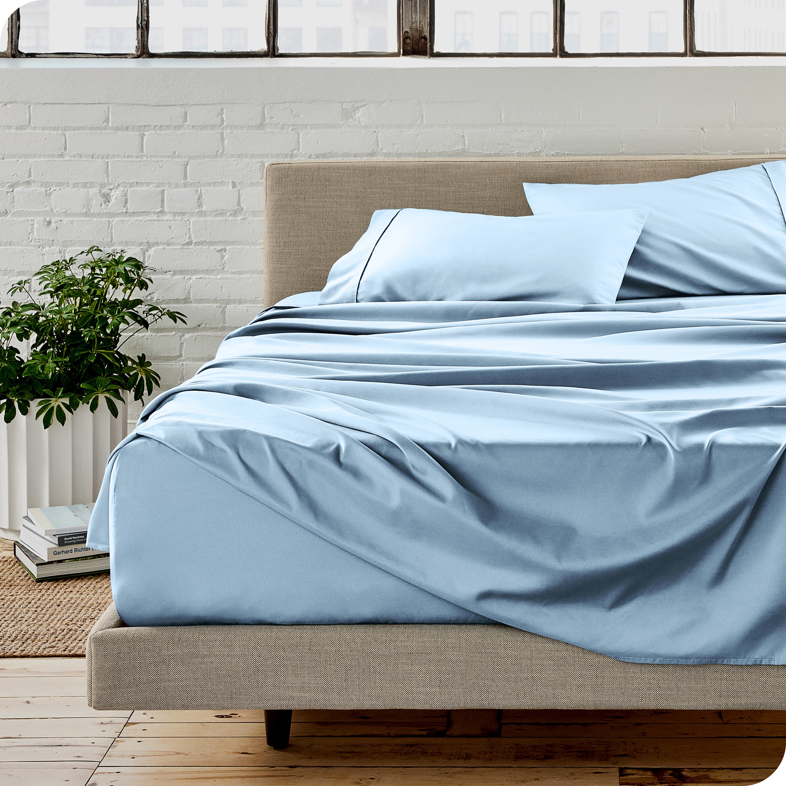 Microfiber sheets on a bed with a brick wall behind it