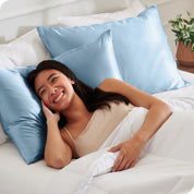 A woman in bed with her head resting on a silk pillowcase covered pillow