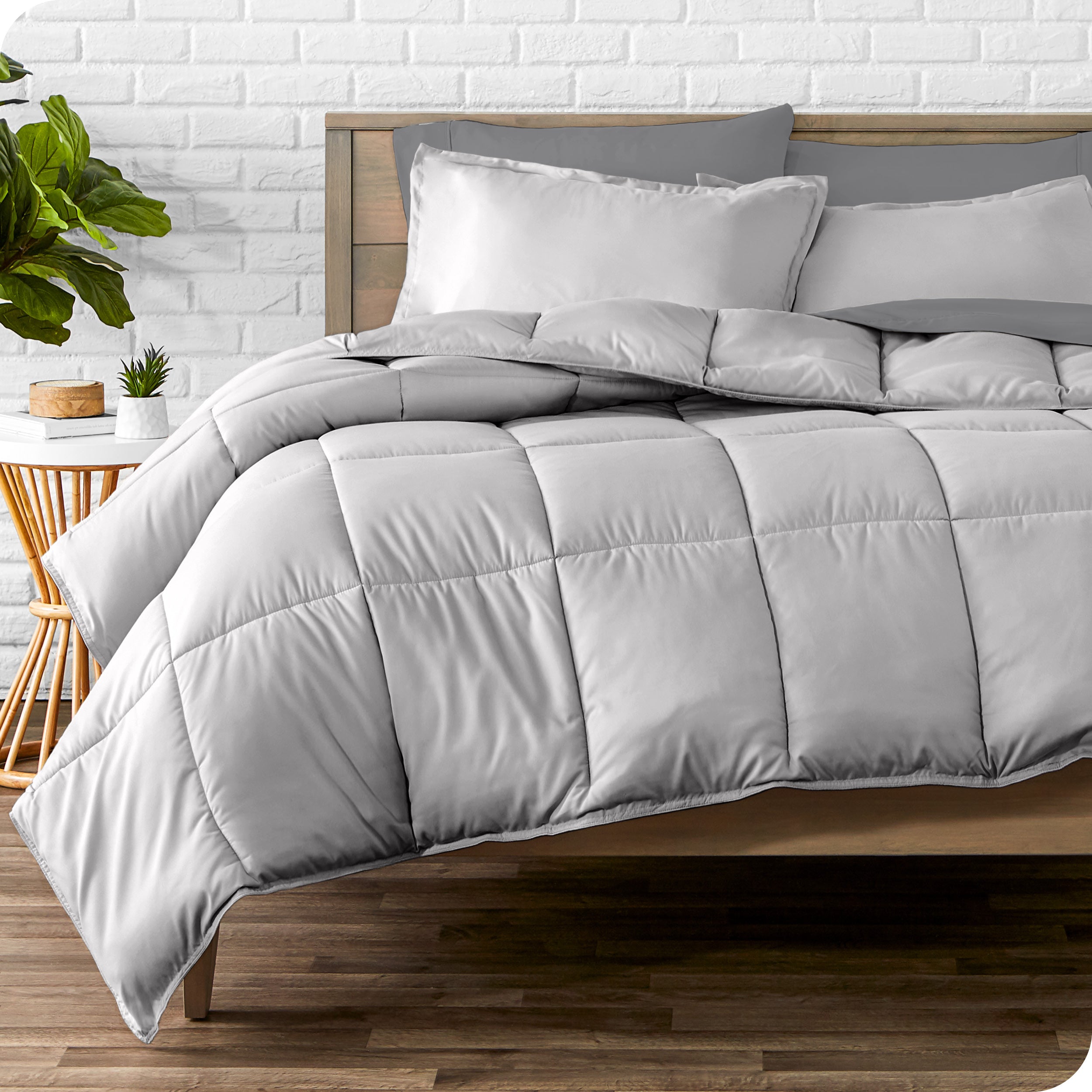 A wooden bed frame with sheets, pillow shams and a comforter on the bed