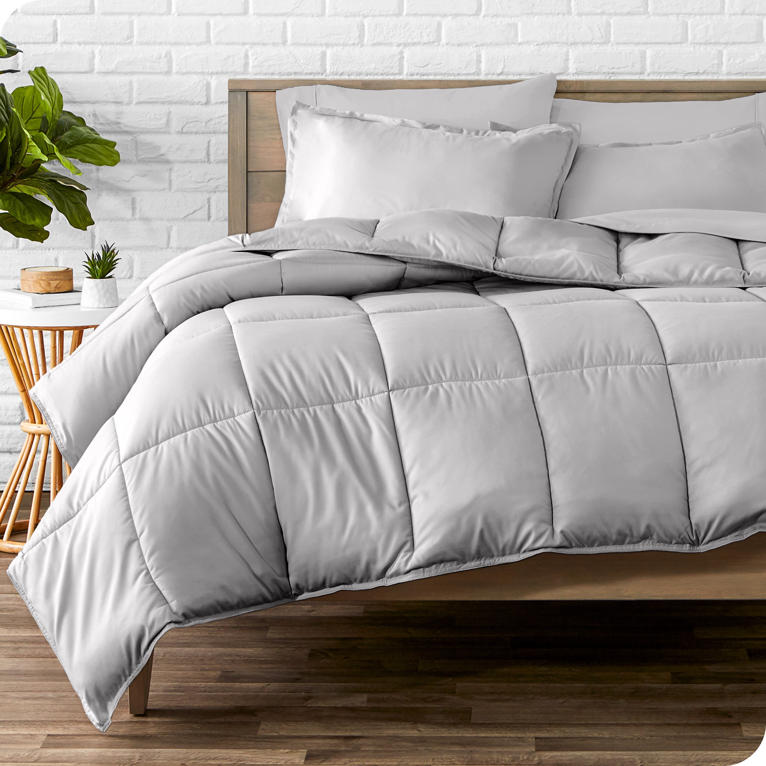 A wooden bed frame with sheets, pillow shams and a comforter on the bed
