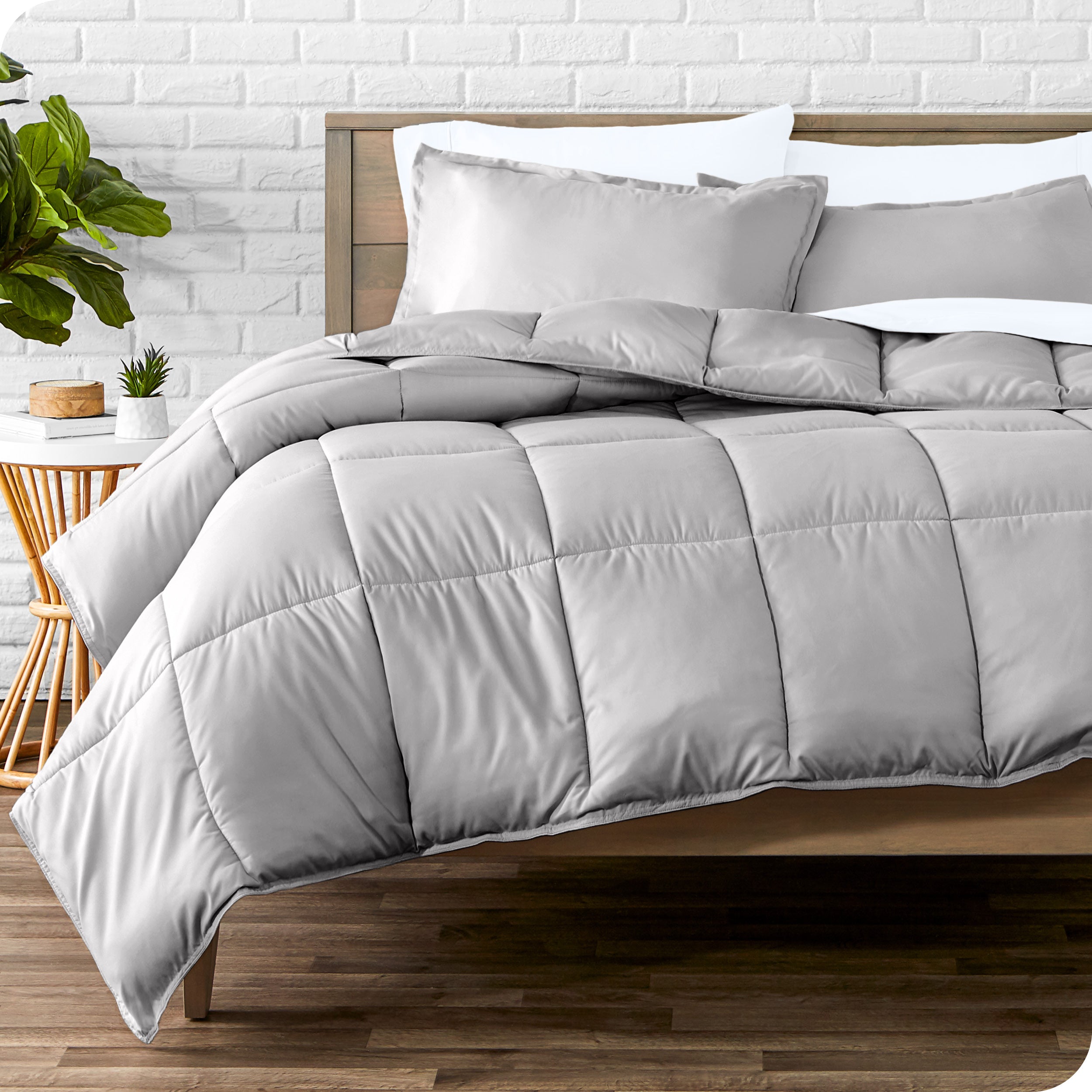 A wooden bed frame with sheets, pillow shams and a comforter on the bed