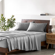 Modern bedroom with a bed against a white wall with a nightstand next to the bed. The bed has bamboo sheets draped over it.