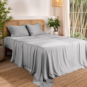 Bamboo sheets on a bed in a bedroom with plants and a window.