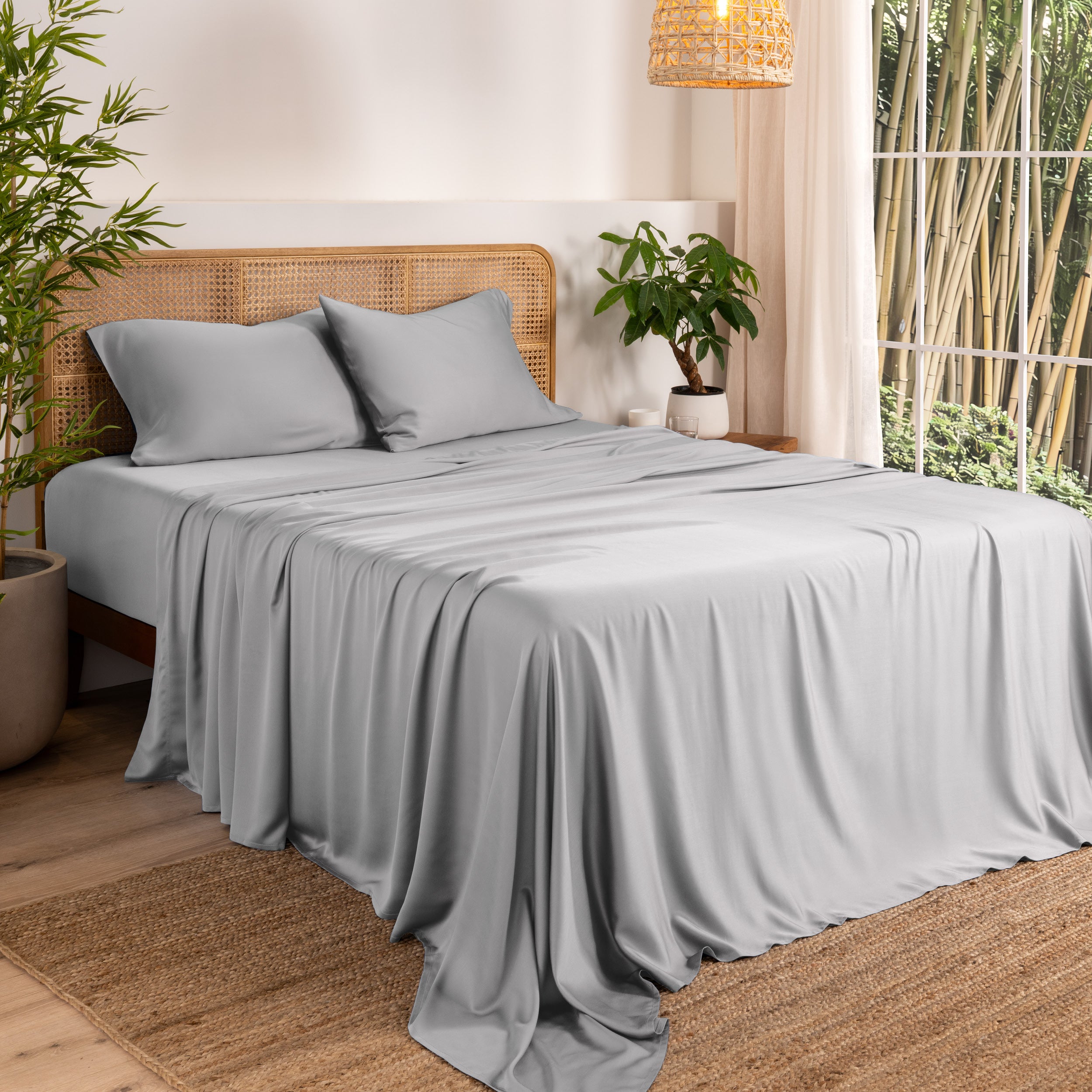 Bamboo sheets on a bed in a bedroom with plants and a window.
