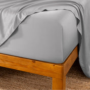 Bed sheets on a wooden bed frame with a brown carpet background