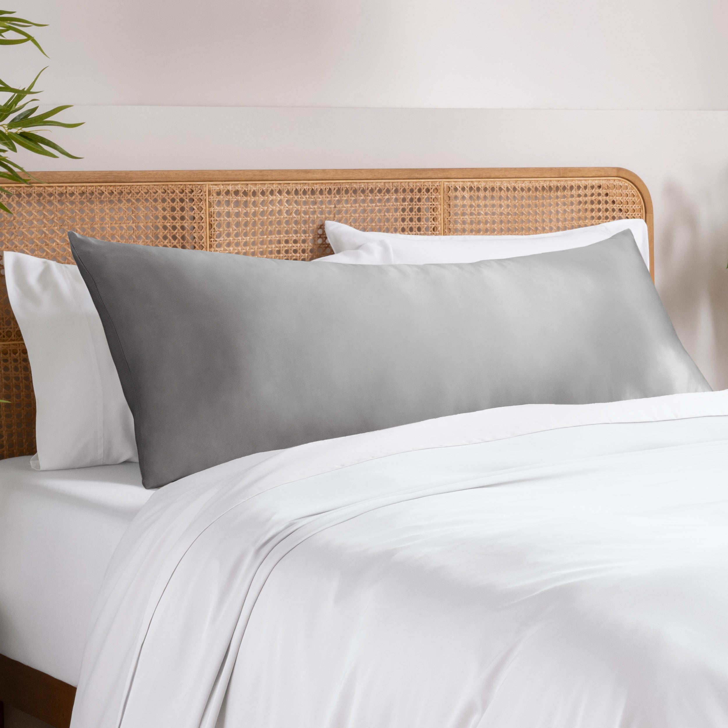 Bamboo pillowcase on a bed with white bedding and a wooden headboard.