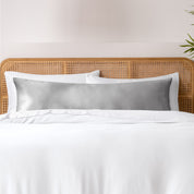 Bamboo body pillowcase on a bed with white bedding and a wicker headboard.