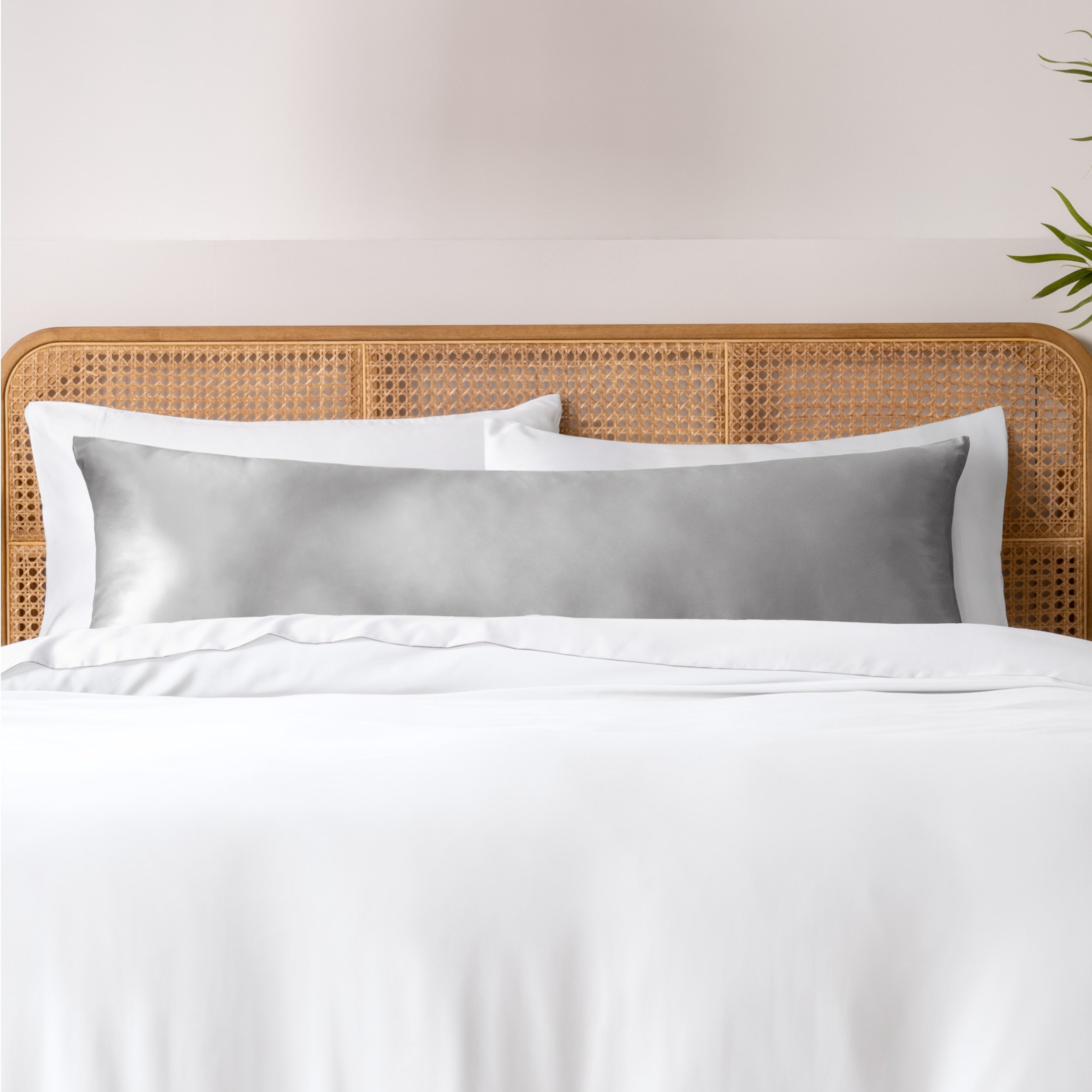 Bamboo body pillowcase on a bed with white bedding and a wicker headboard.