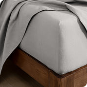 Close up of the corner of a mattress with a fitted sheet and flat sheet on it