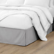The corner of a bed with a bed skirt and comforter on it