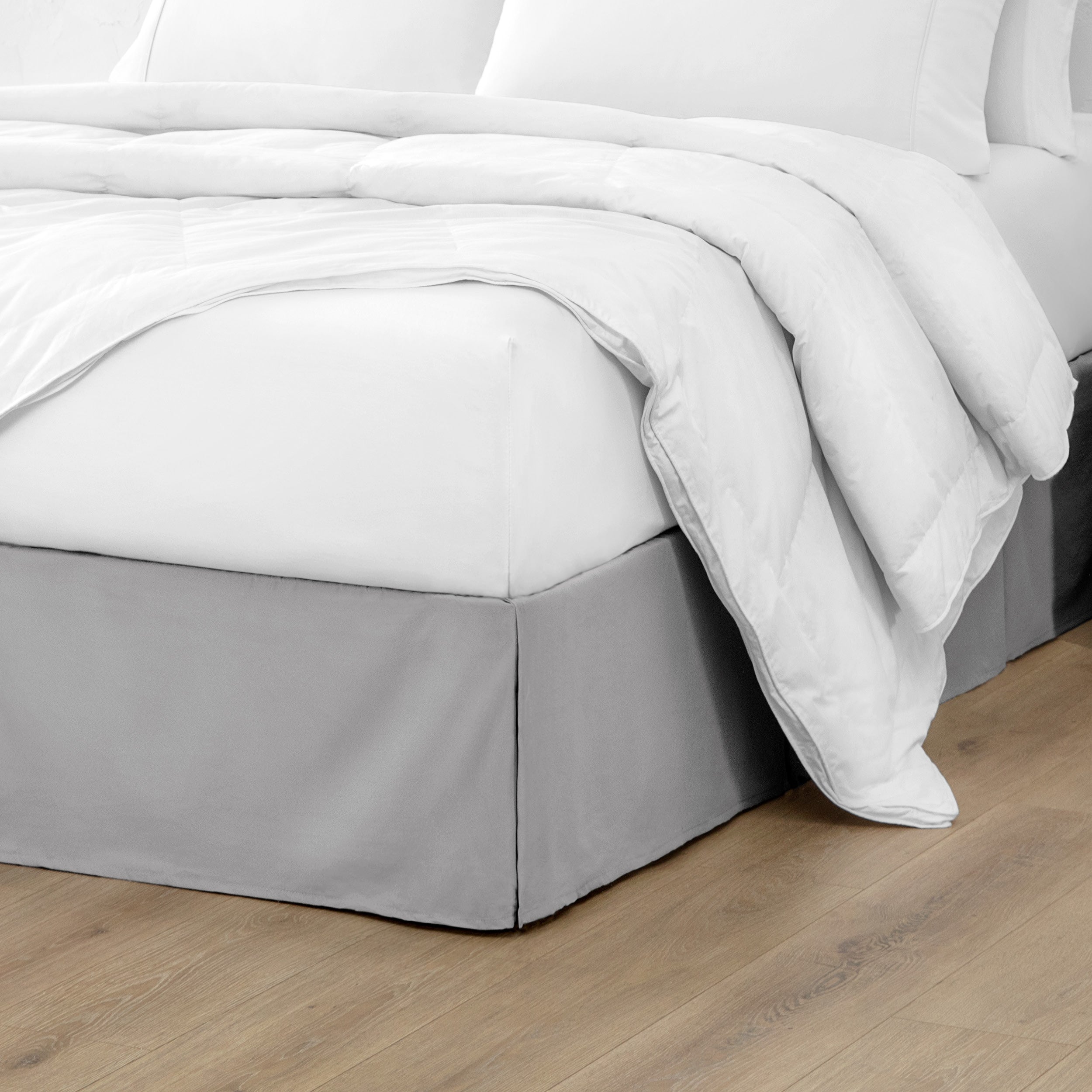 The corner of a bed with a bed skirt and comforter on it