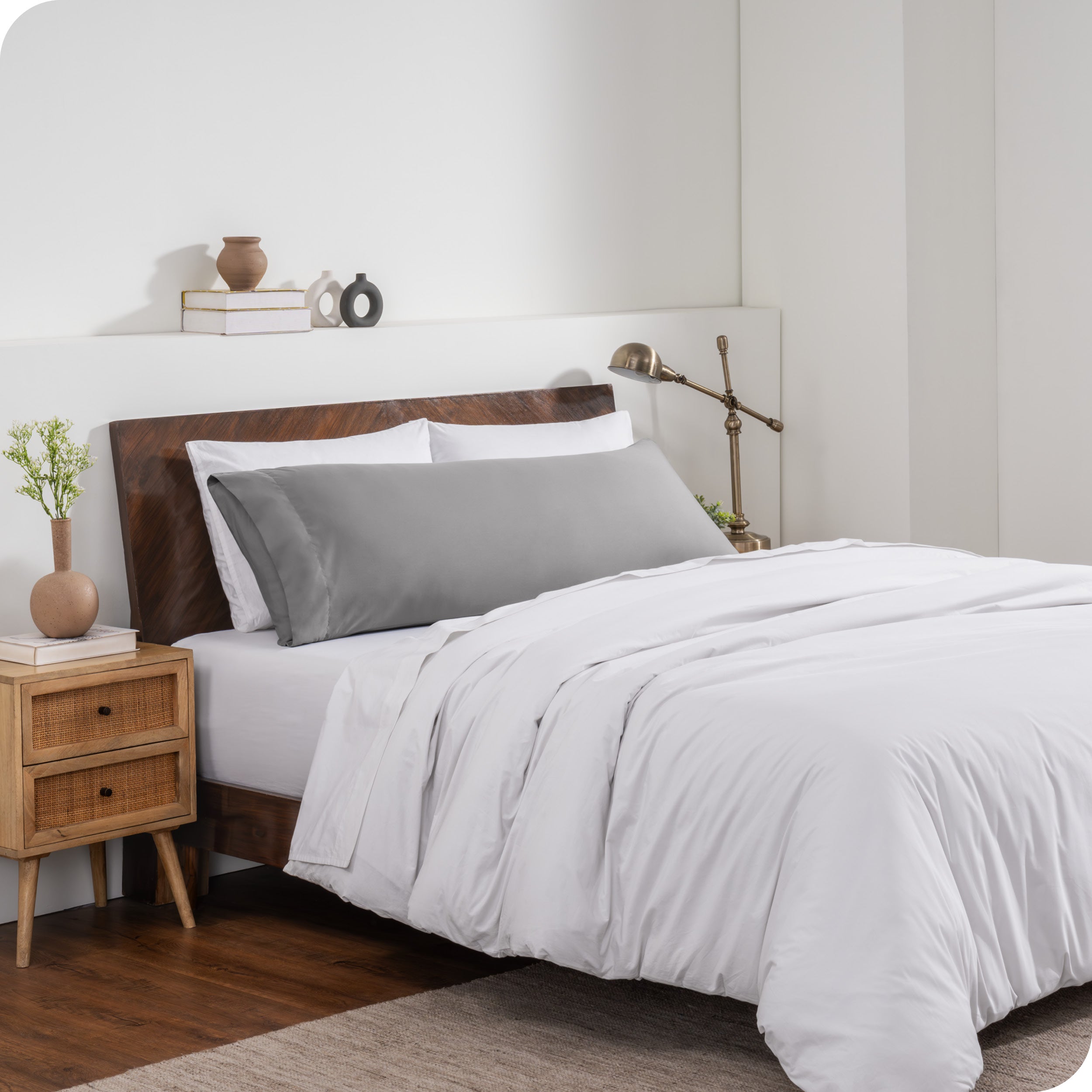 A body pillow cover on a pillow on a bed made with all white bedding