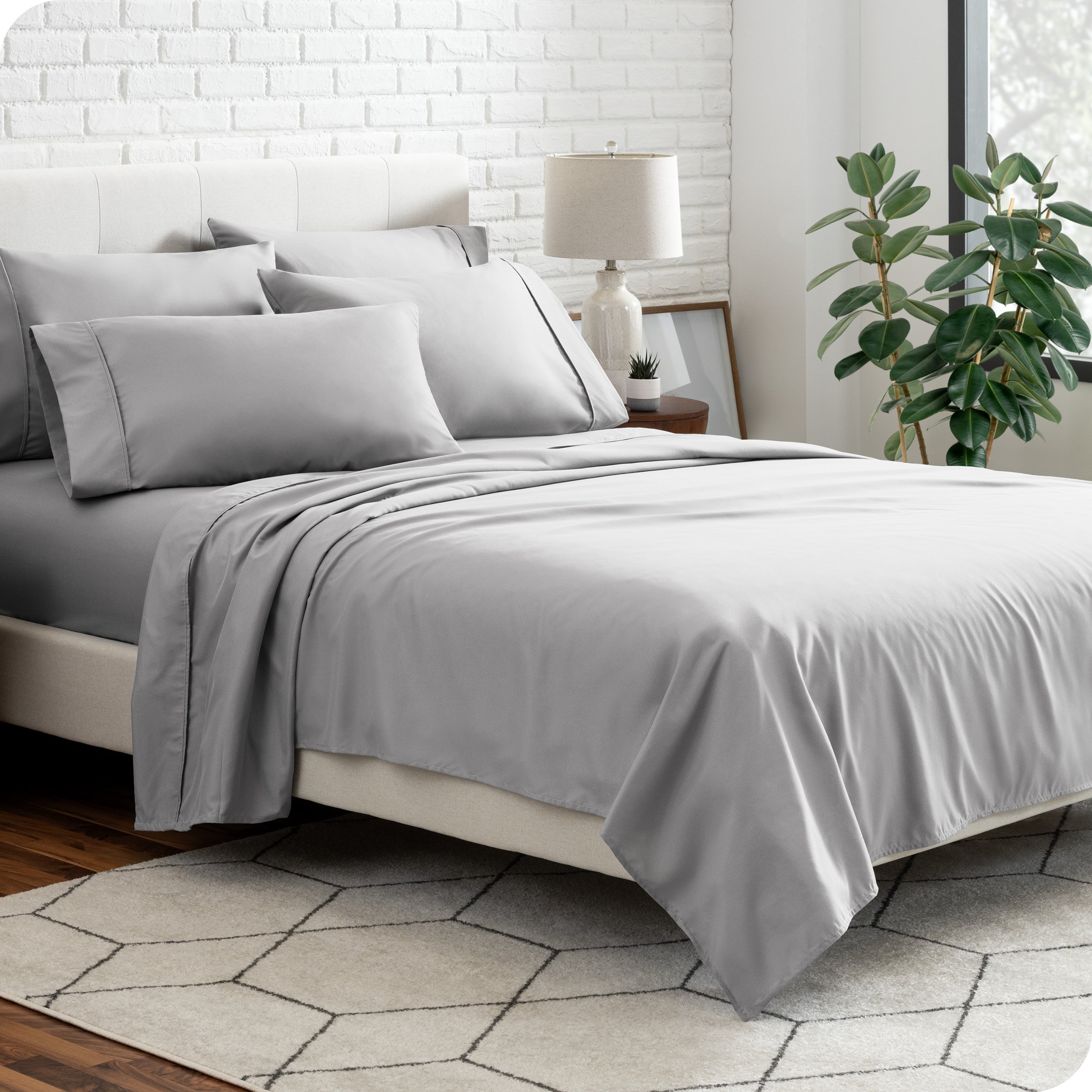 A bedroom setting with a bed made with the microfiber bed sheets and four pillows.