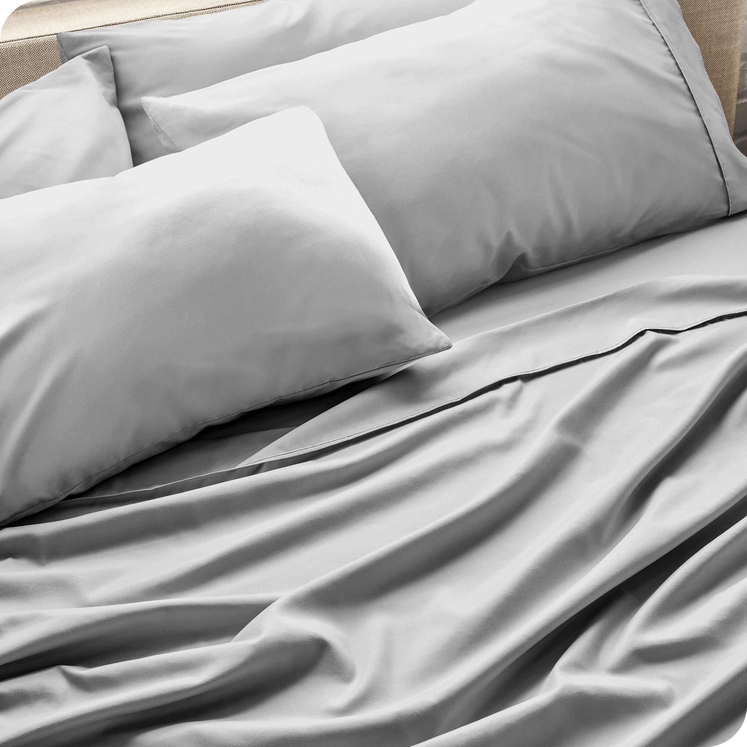 Close up of the microfiber bed sheets on a bed with four pillows.