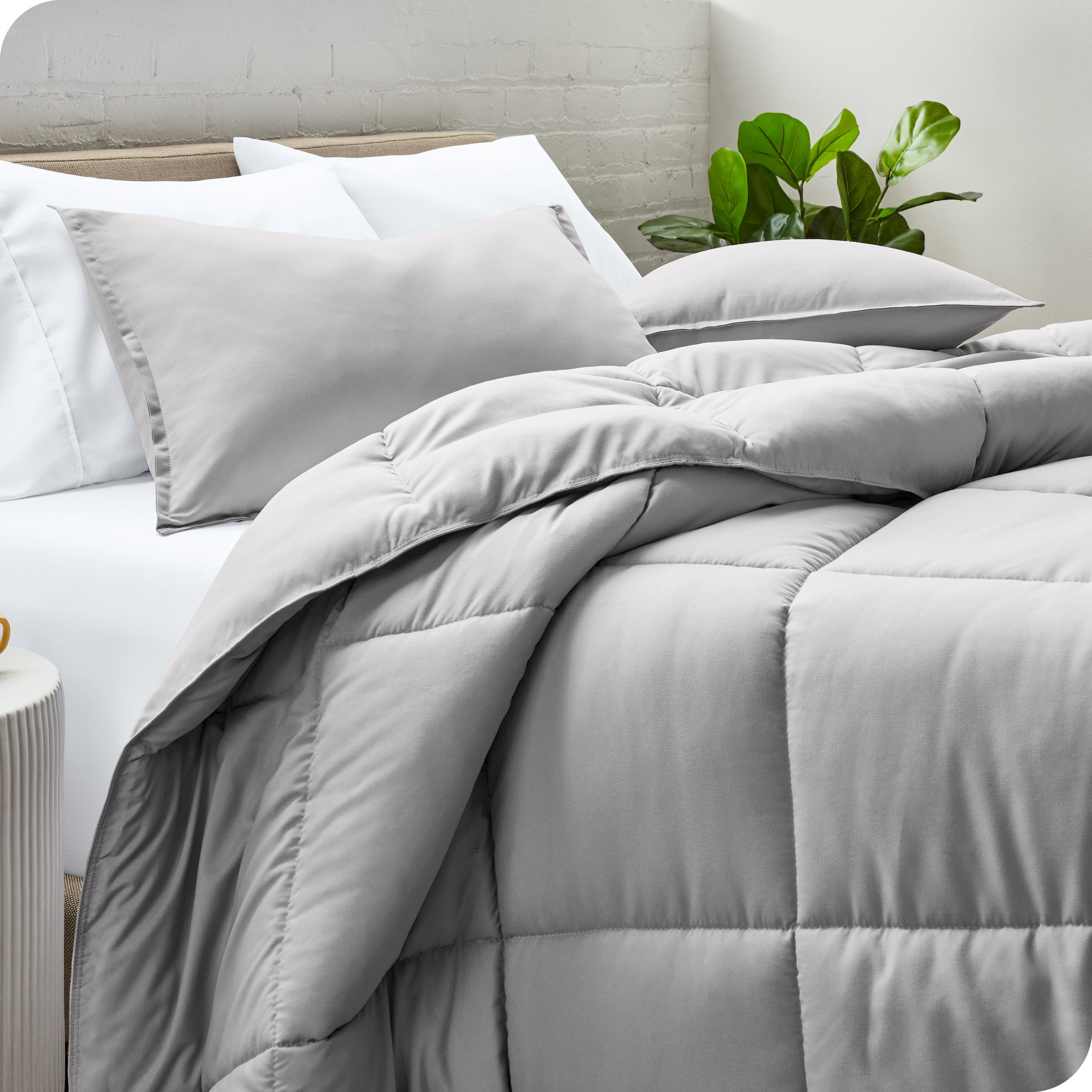A side view of a modern bed with a comforter set and pillows on the bed