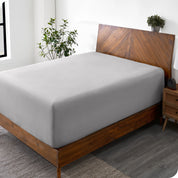 A wide corner view of a modern bed made with a microfiber fitted sheet on the mattress. 