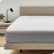 A bed with a microfiber fitted sheet on the mattress. 