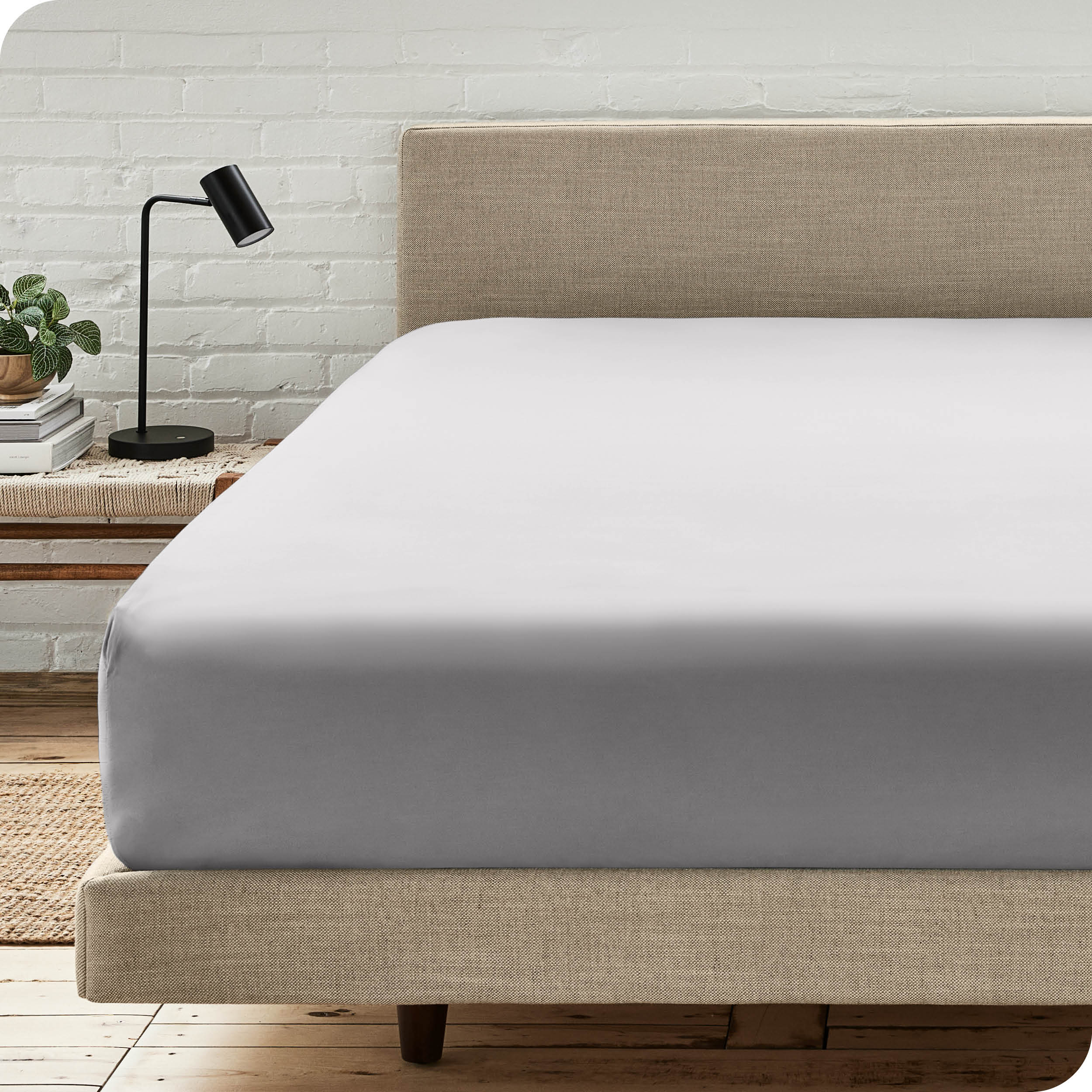 A bed with a microfiber fitted sheet on the mattress. 